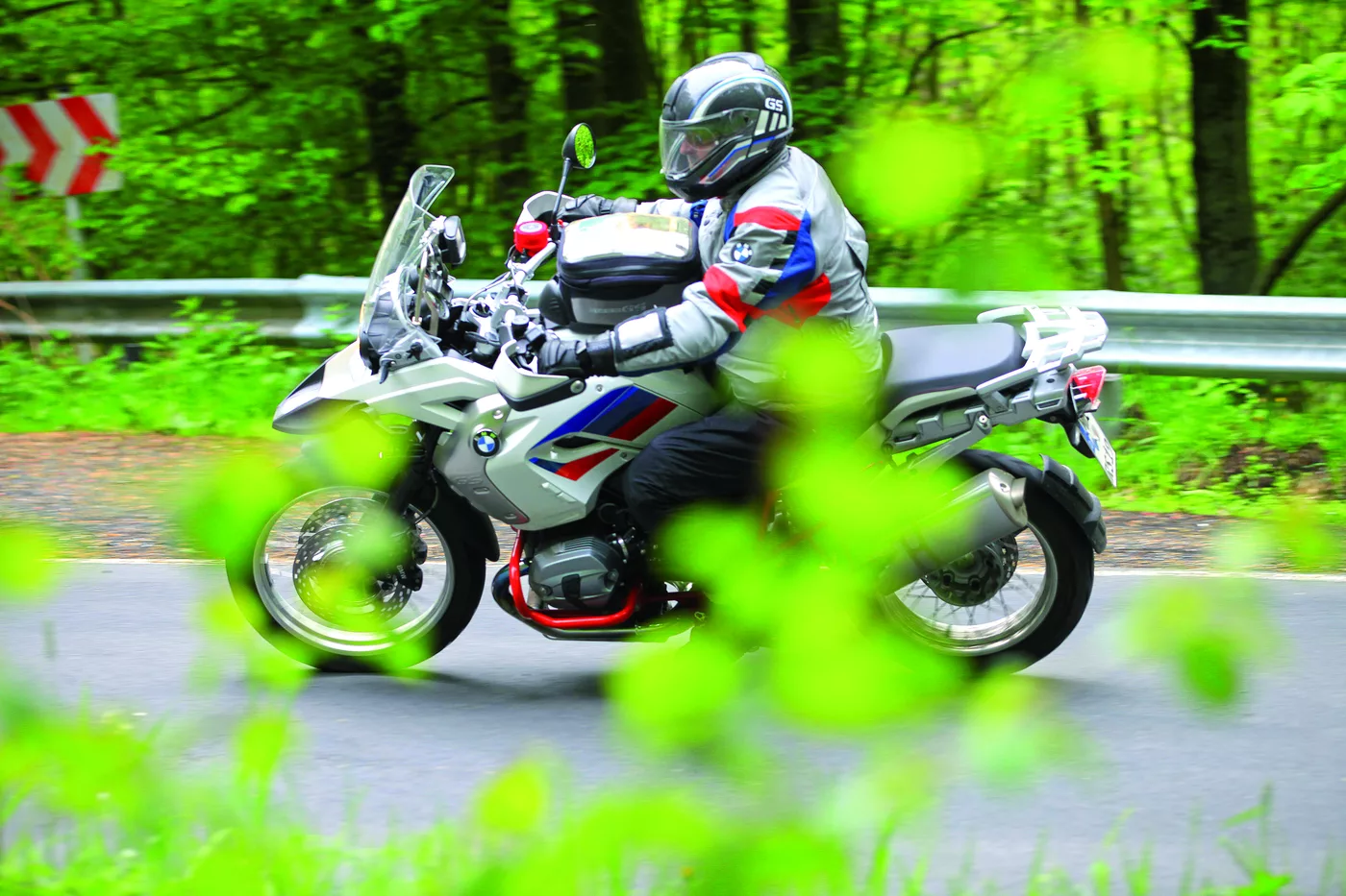 Motorrad in einer Kurve, im Vordergrund grüne Blätter